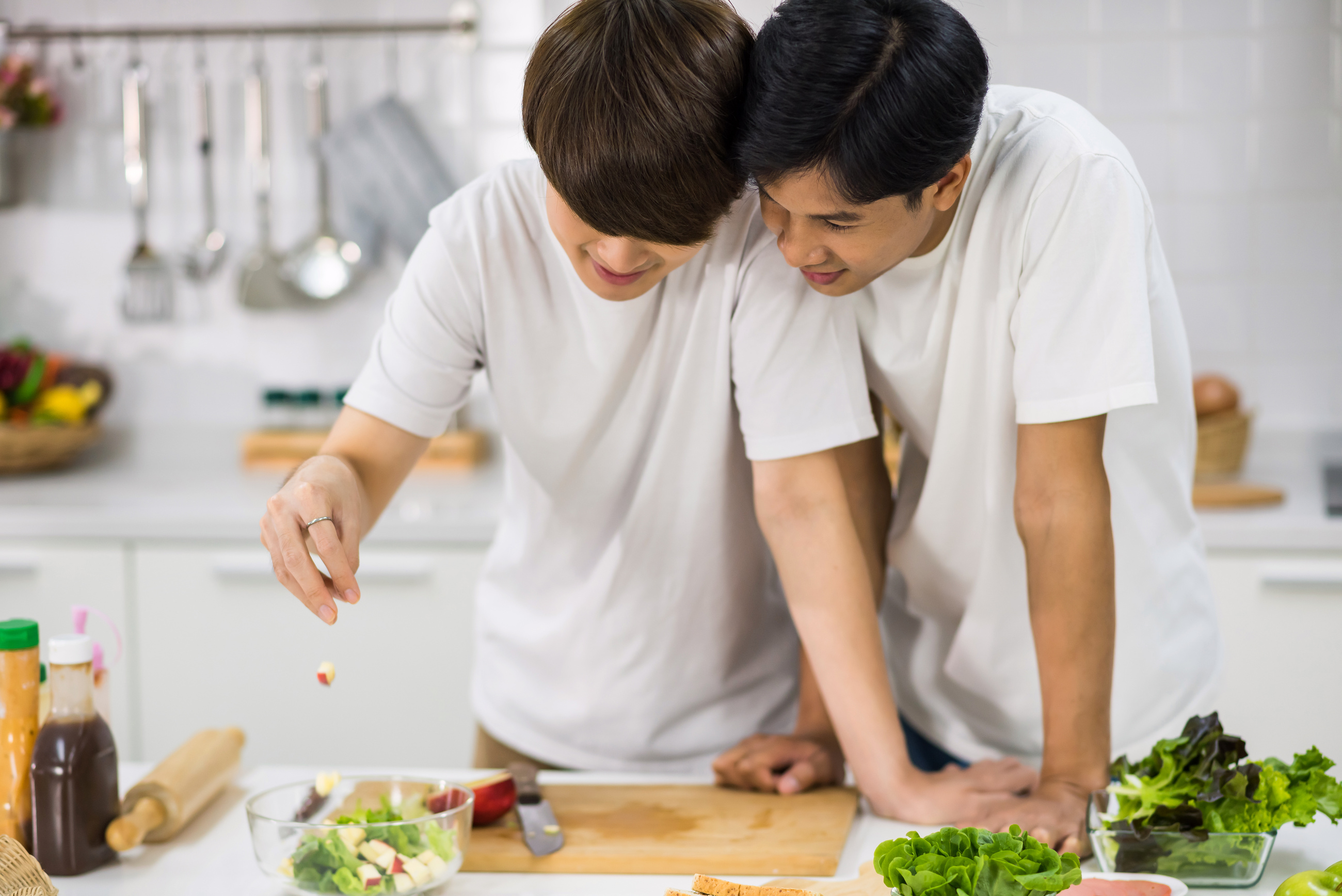 Asian LBGT gay couple cook salad in kitchen
